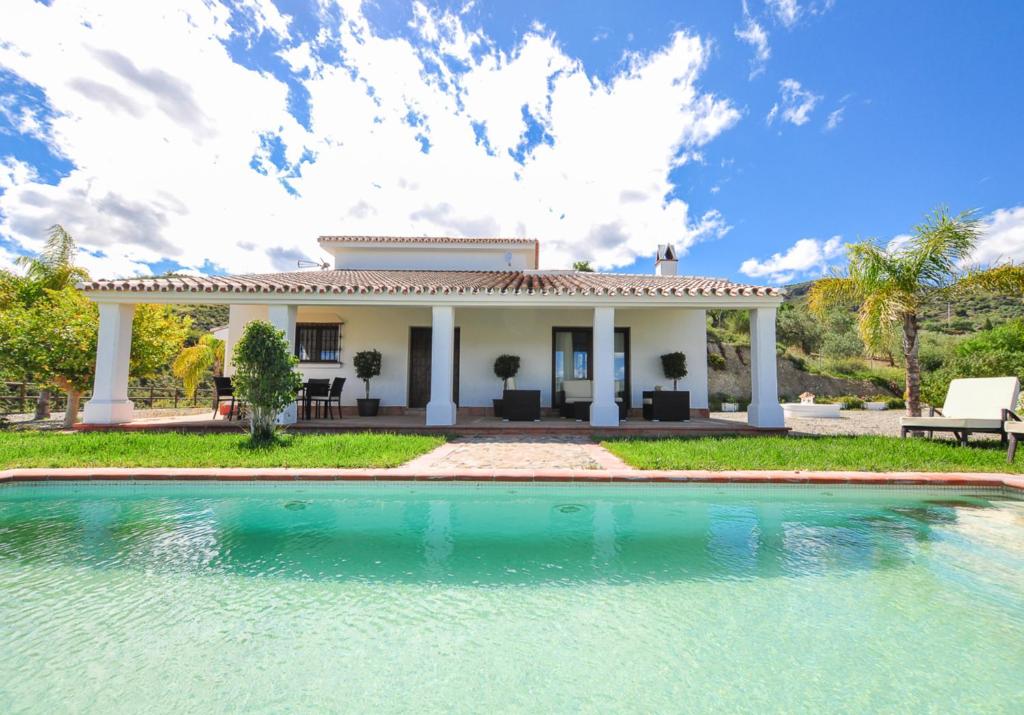 una villa con piscina di fronte a una casa di El Capricho Villa Rural Caminito del Rey ad Alora