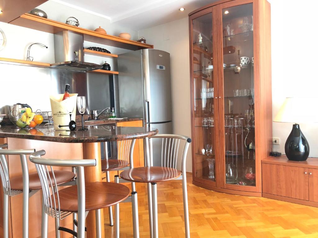 a kitchen with a bar with chairs and a refrigerator at La Dolce Vita Abbazia in Opatija