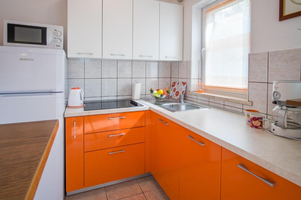 a kitchen with orange cabinets and a white refrigerator at Apartments Stasic in Vrbnik
