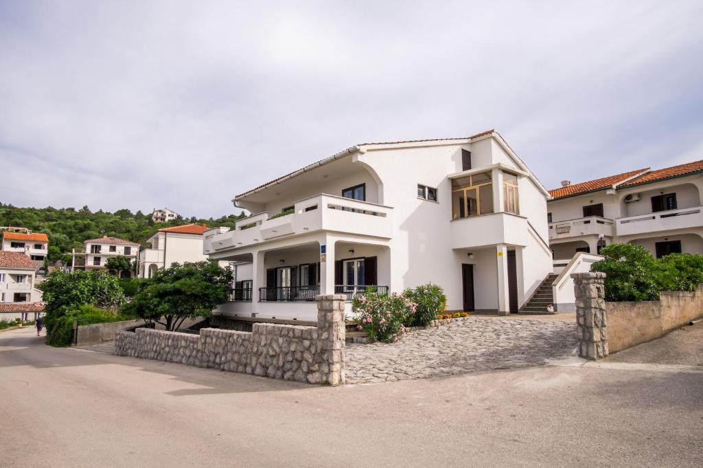 a white house with a stone wall at Apartments Stasic in Vrbnik