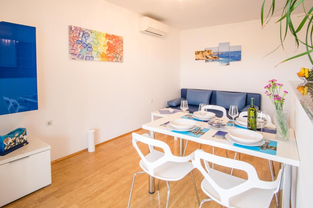 a dining room with a white table and chairs at Apartments Stasic in Vrbnik