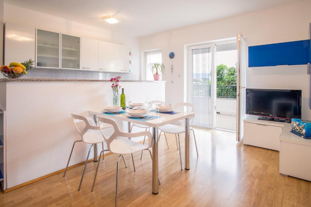 a kitchen and dining room with a white table and chairs at Apartments Stasic in Vrbnik