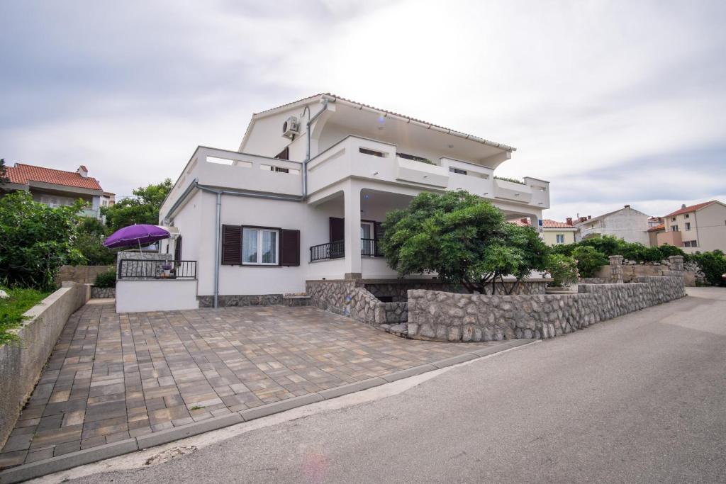 a white house with a stone retaining wall at Apartments Stasic in Vrbnik