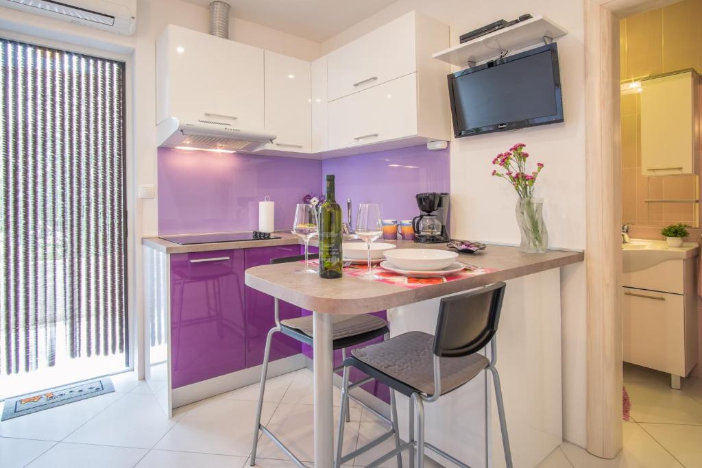 a kitchen with purple cabinets and a table with stools at Apartments Stasic in Vrbnik