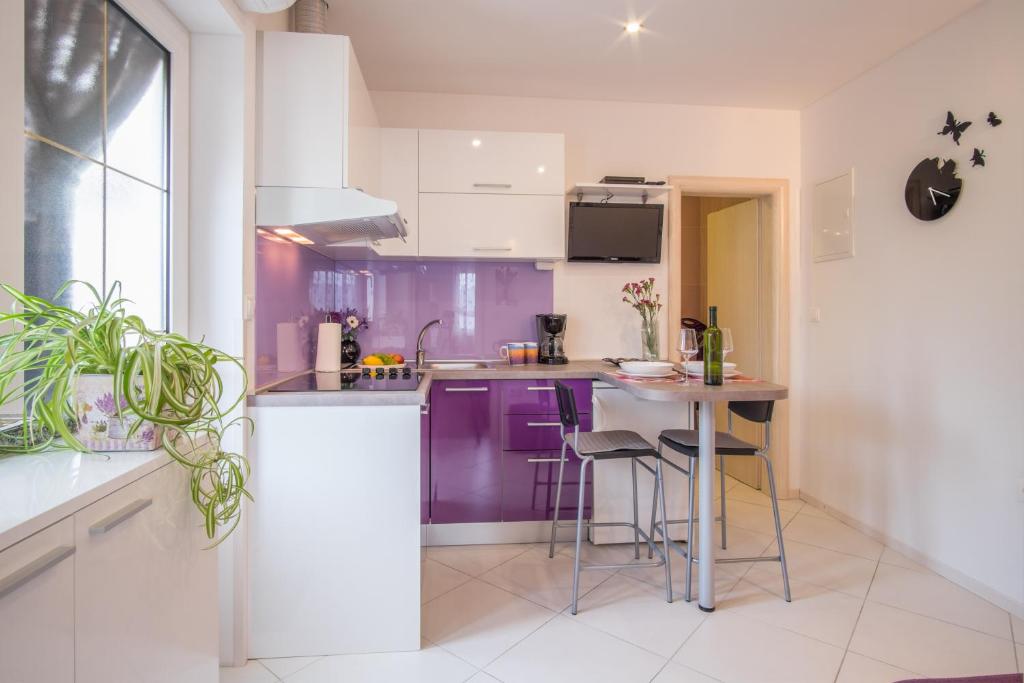 a kitchen with purple cabinets and a table with stools at Apartments Stasic in Vrbnik