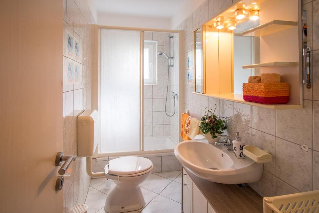 a bathroom with a sink and a toilet and a mirror at Apartments Stasic in Vrbnik