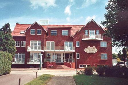 um grande edifício de tijolos vermelhos com uma varanda em Hotel Garni Bendiks em Horumersiel