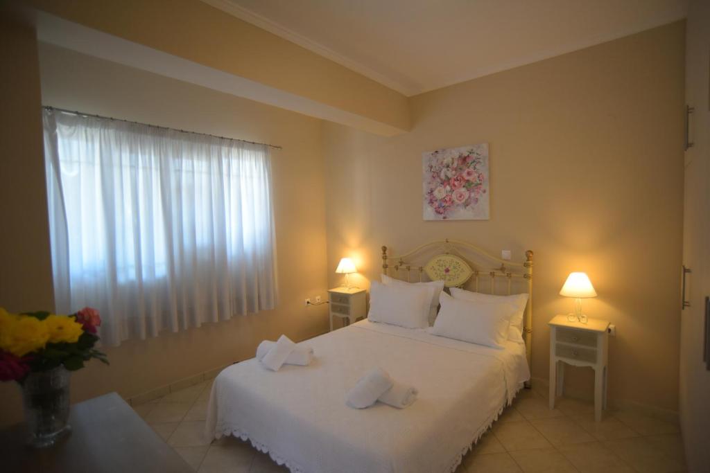 a bedroom with a white bed with two towels on it at G & K City Apartments in Lefkada Town