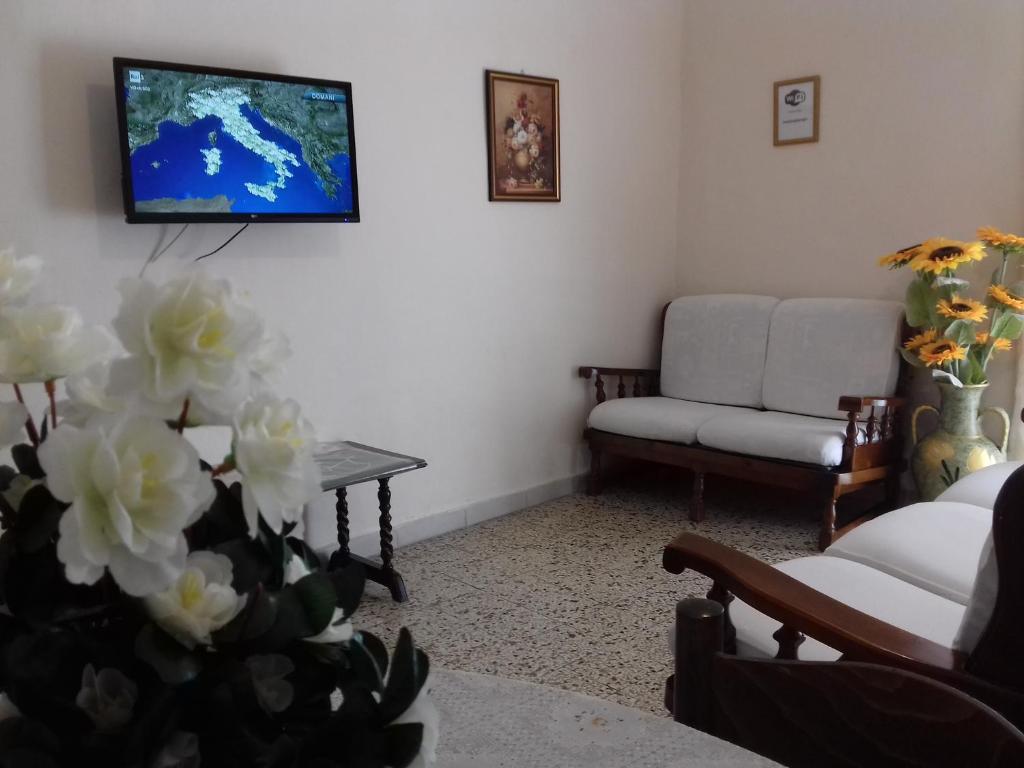 ein Wohnzimmer mit einem Sofa und einem TV an der Wand in der Unterkunft Casa Luigi Sergio - affitto breve in Santo Stefano di Camastra