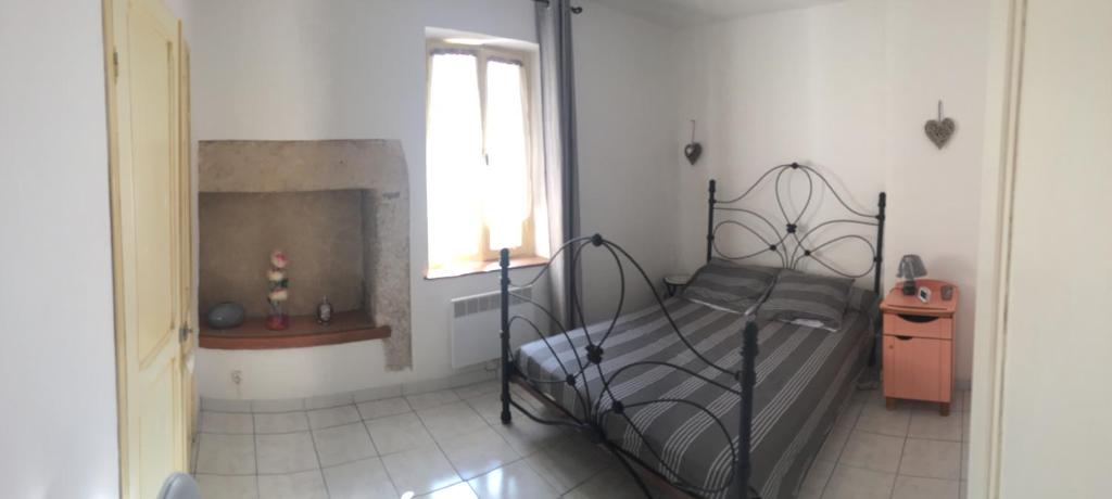 ein Schlafzimmer mit einem Metallbett und einem Kamin in der Unterkunft Le Gite des Remparts in Ginestas