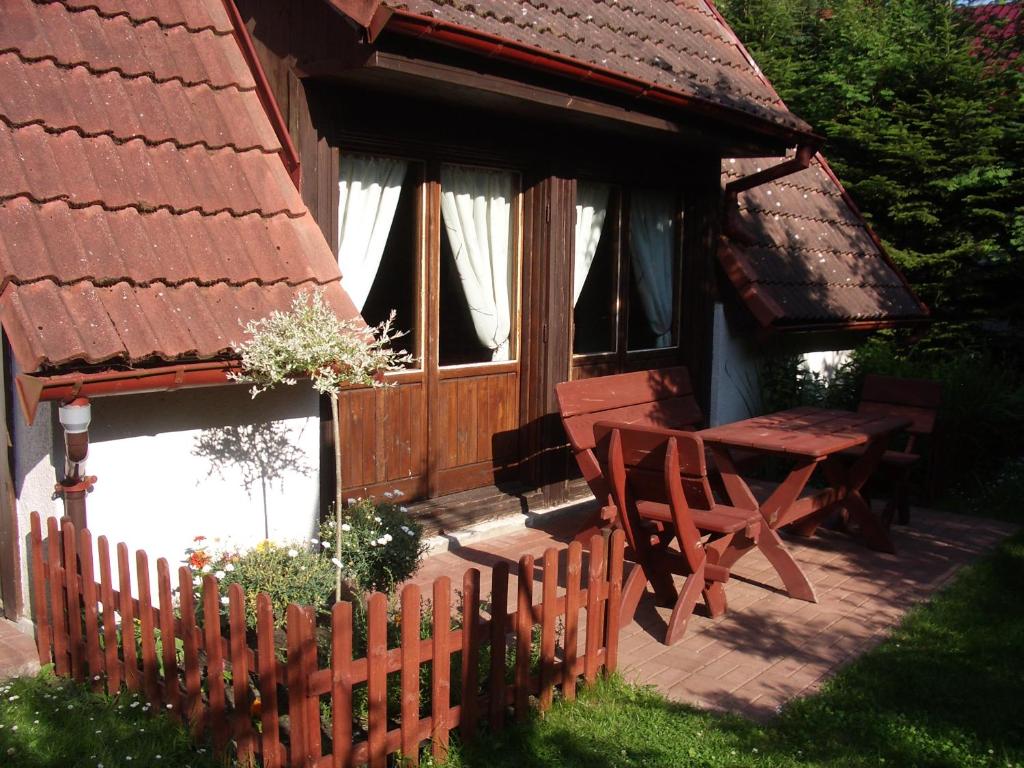 a wooden house with a wooden table and a wooden fence at Domek Pod Różami in Poddąbie