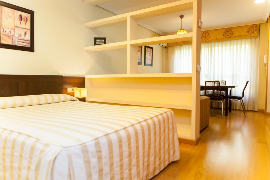 a bedroom with a bed and a dining room with a table at Apartamentos Tres Luces in Vigo