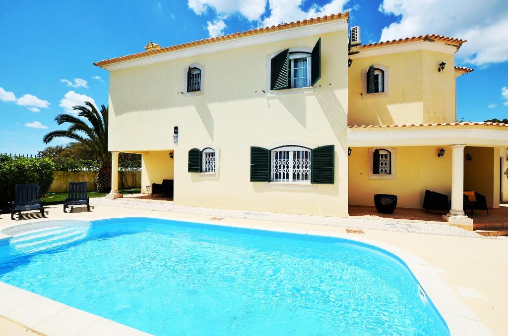 a villa with a swimming pool in front of a house at Suites & Beds DP Albufeira in Albufeira