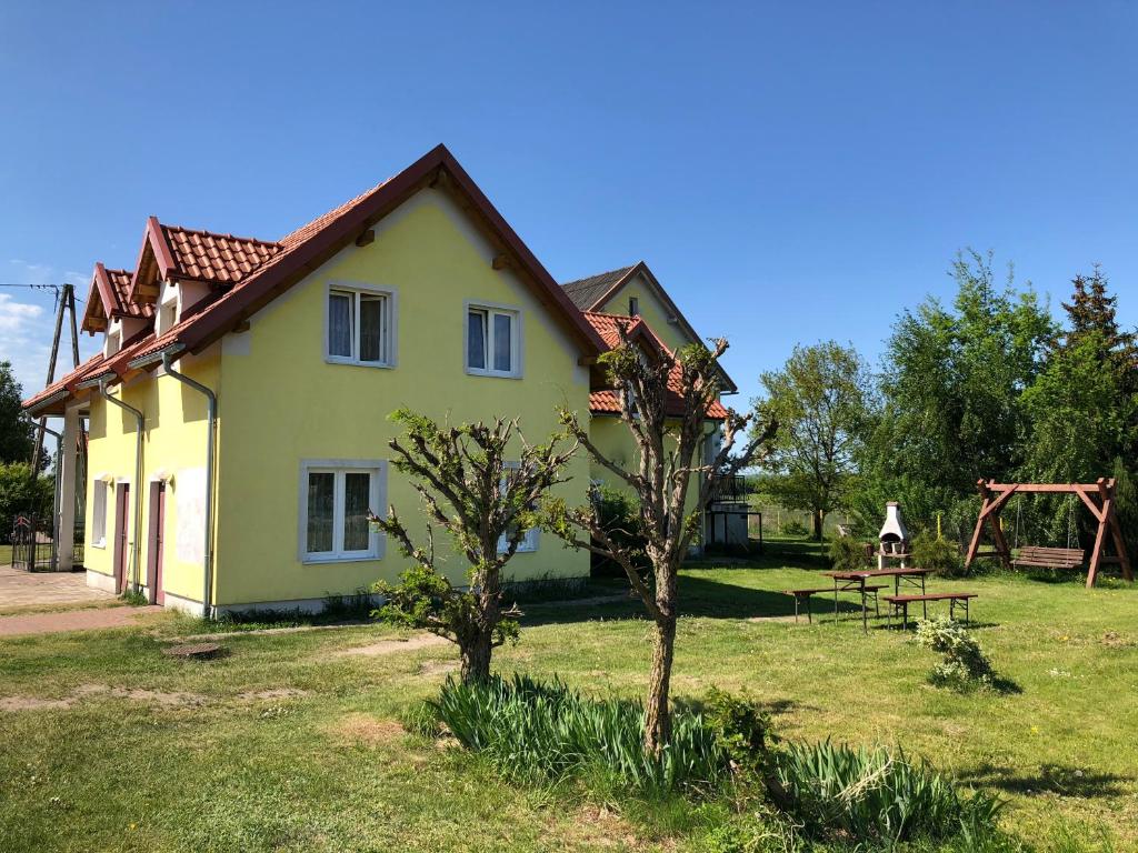 a yellow house with a picnic table in a yard at Agropensjonat Furtak in Pasłęk