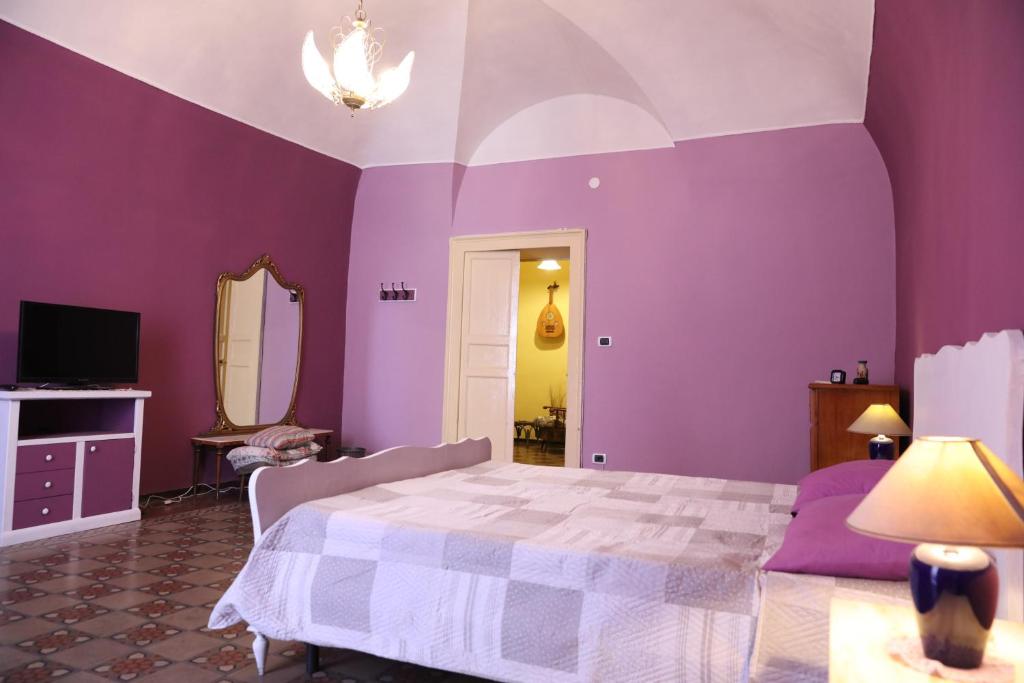 Dormitorio púrpura con cama y espejo en la locanda del centro storico, en Catania