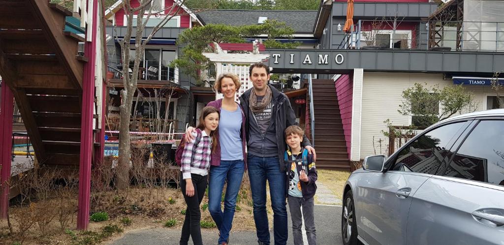 a man and two children standing next to a car at Gyeongju Tiamo Pension in Gyeongju