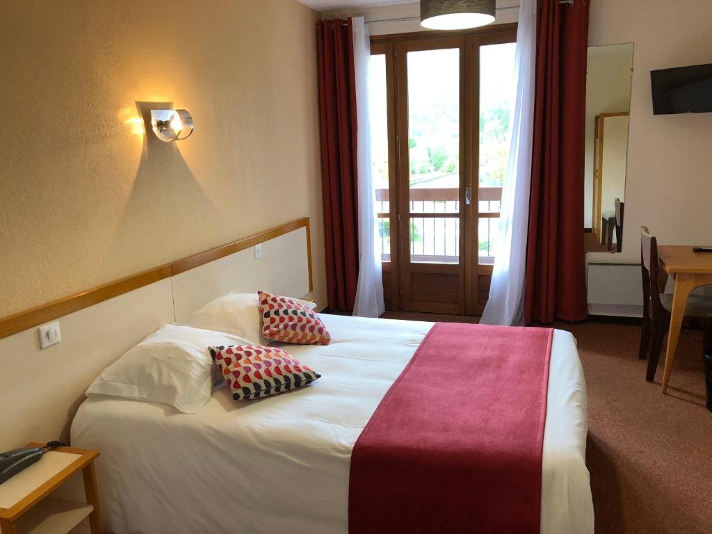 a hotel room with a bed with two pillows on it at Le Vallon in Ispagnac