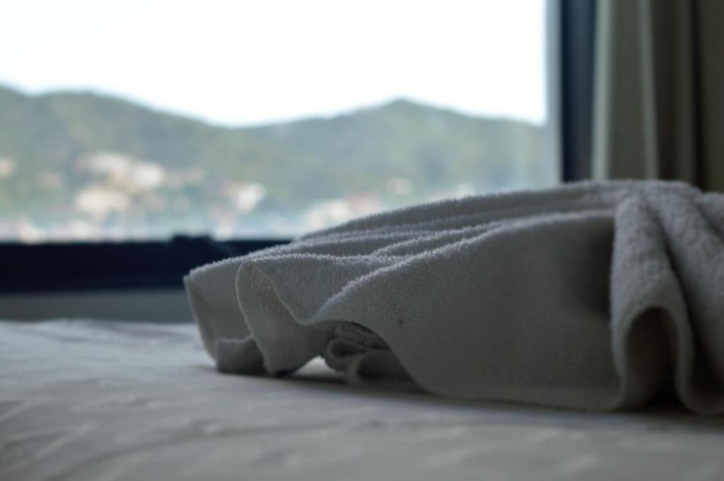 Una toalla blanca sobre una cama con ventana en Apart Riviera Tower Suites en Villa Carlos Paz