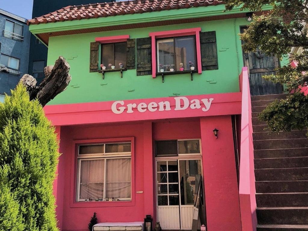 un edificio verde y rosa con un cartel que diga día verde en Greenday Guesthouse, en Jeju