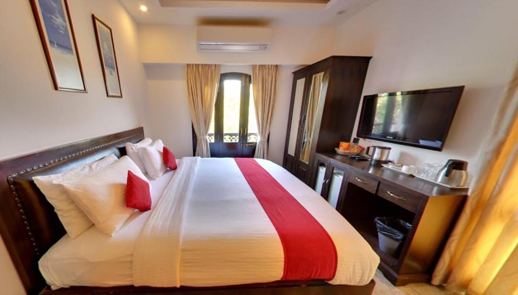 a hotel room with a bed and a television at Calangute Grande in Calangute