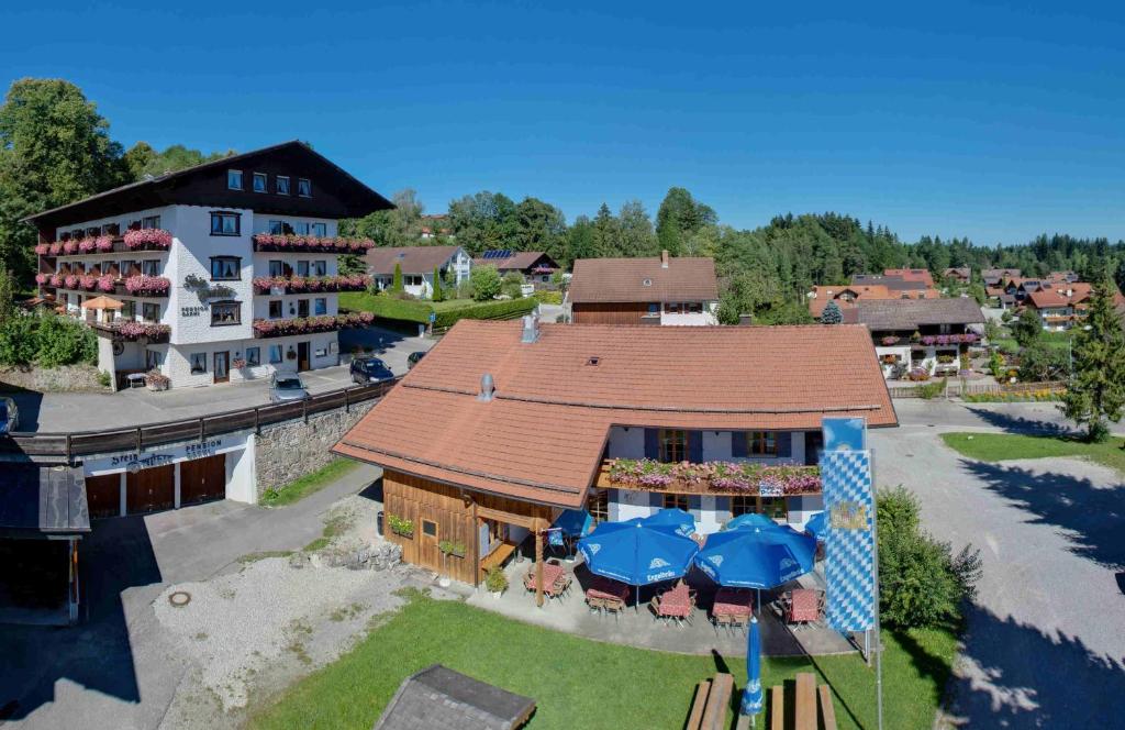 eine Luftansicht eines Gebäudes mit Tischen und Sonnenschirmen in der Unterkunft Steigmühle Pension Garni in Füssen