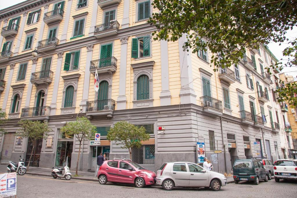 un grande edificio con macchine parcheggiate di fronte di 319 al Duomo a Napoli