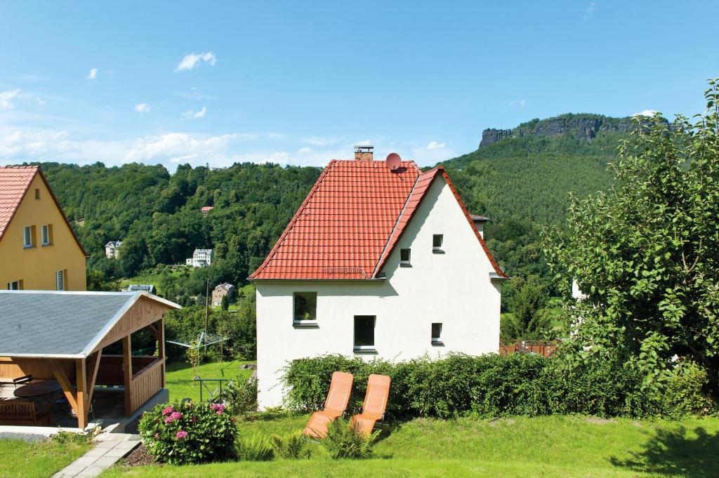 una casa bianca con un tetto rosso e alcune sedie di Ferienwohnung Liliensteinblick a Königstein