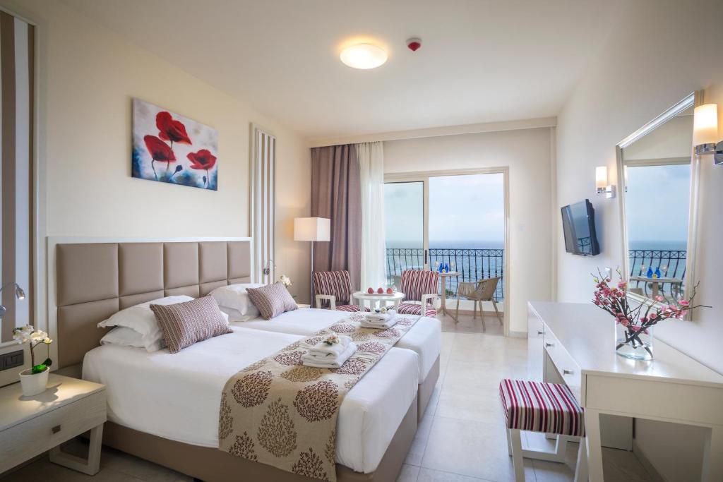 a hotel room with a large bed and a table at Aquamare Beach Hotel & Spa in Paphos