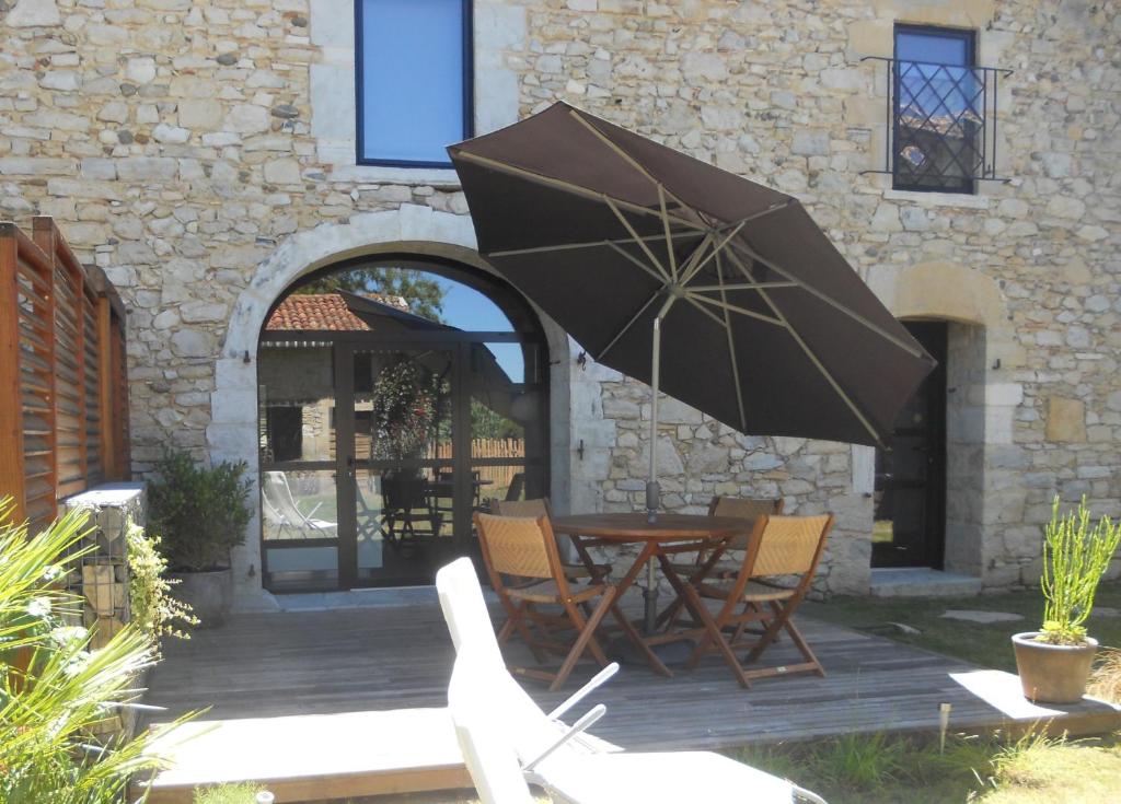 une terrasse avec une table, des chaises et un parasol dans l'établissement Gite Carpe Diem, à Port-de-Lanne