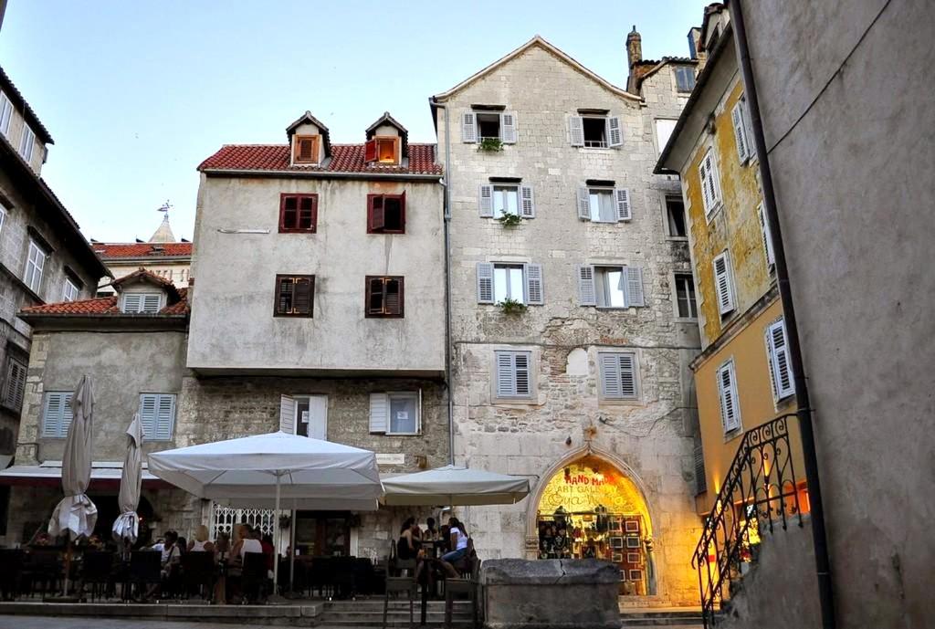 an old building with tables and umbrellas in front of it at Apartment Piazzeta De Luxe in Split