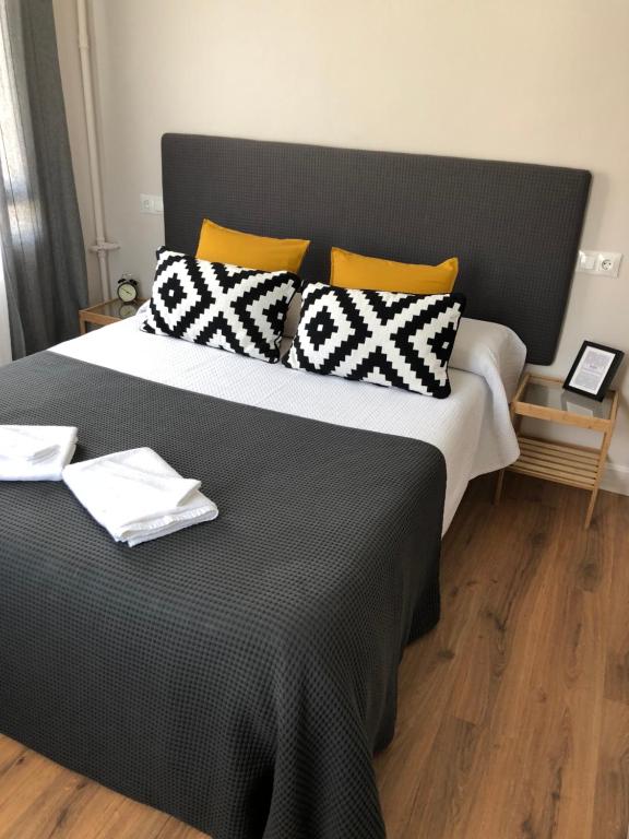 a large bed with black and white pillows on it at Pensión Fernández in Vega de Valcarce