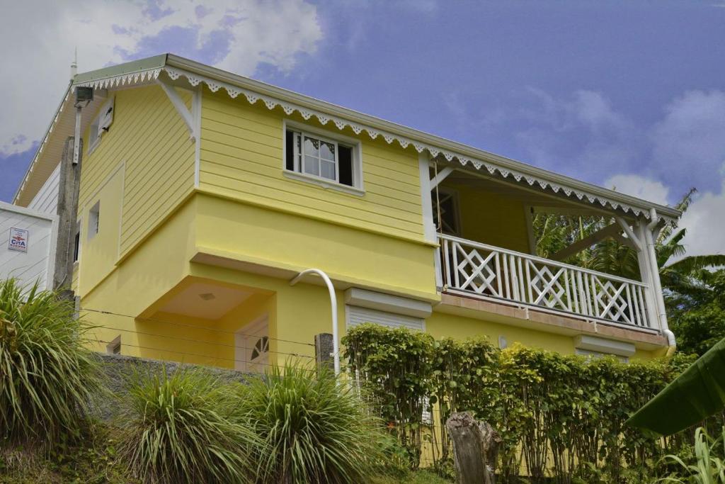 a yellow house with a balcony and a fence at Résidence Kay Mamy Zèt in Le François