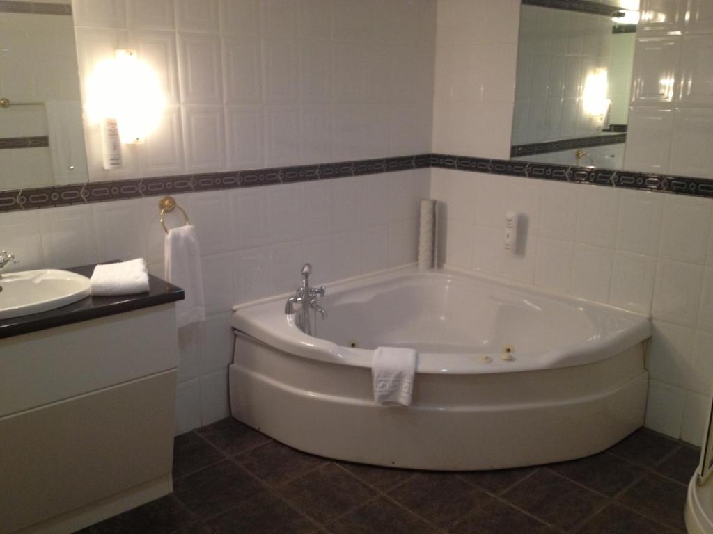 a white bathroom with a tub and a sink at Royal Court Hotel in Portrush