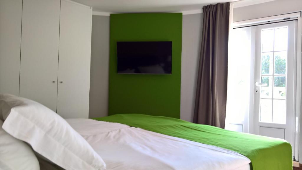 a bedroom with a green wall and a bed at Quinta do Cabo Guesthouse in Sintra