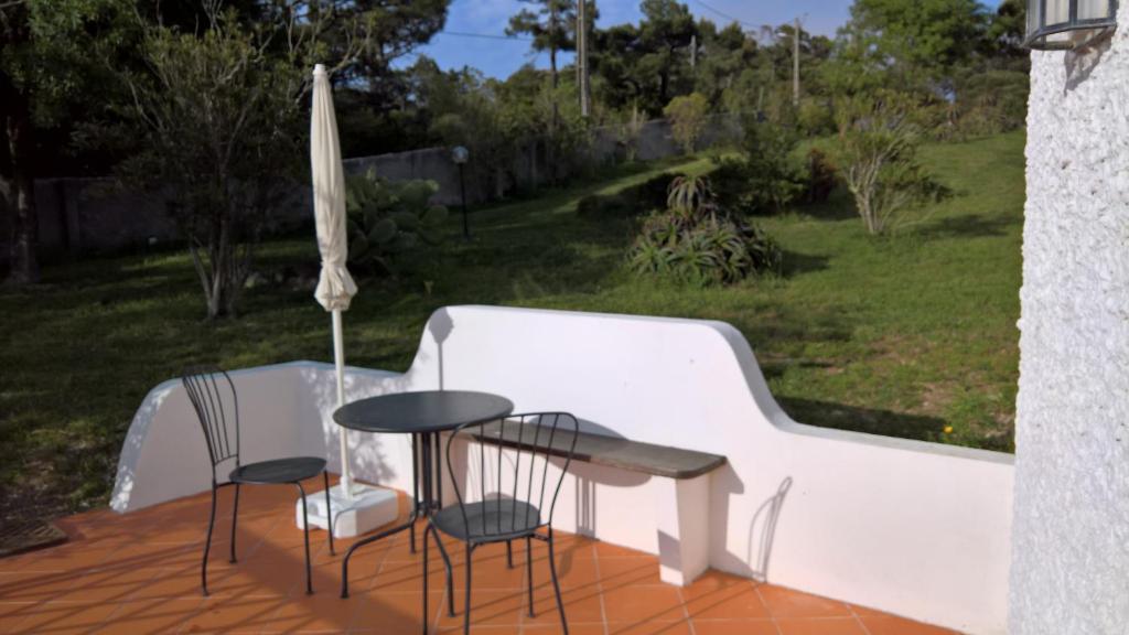 a patio with a table and chairs and an umbrella at Quinta do Cabo Guesthouse in Sintra