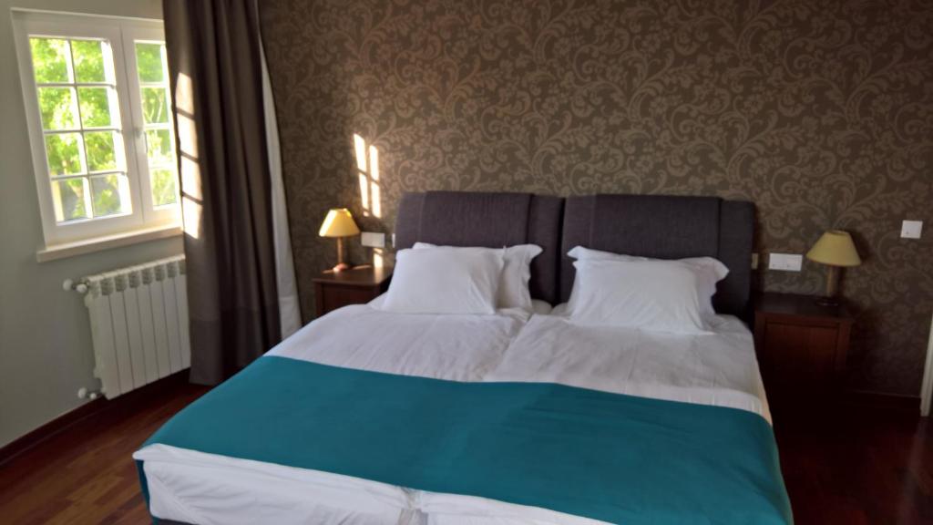 a bedroom with a large bed with blue and white sheets at Quinta do Cabo Guesthouse in Sintra