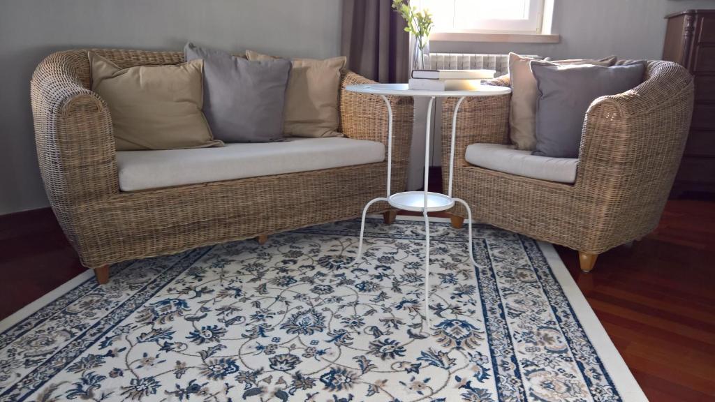 two wicker chairs and a table in a living room at Quinta do Cabo Guesthouse in Sintra