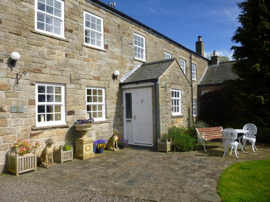 uma casa de pedra com uma porta branca e um banco em The Gin Gan em Hexham