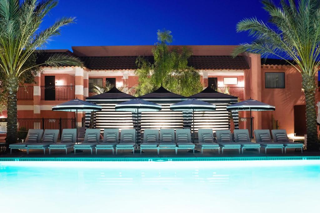 una piscina con sillas y sombrillas frente a un hotel en Sands Hotel and Spa en Indian Wells
