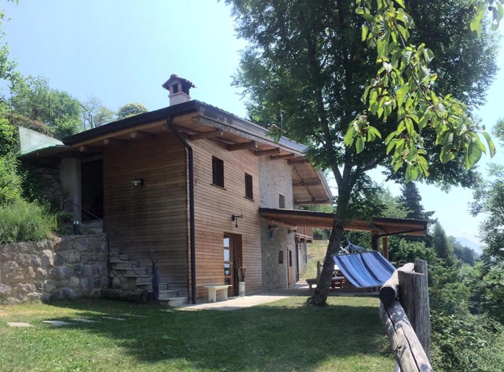 una casa de madera con un banco delante en Chalet Tre Santelle, en Bossico