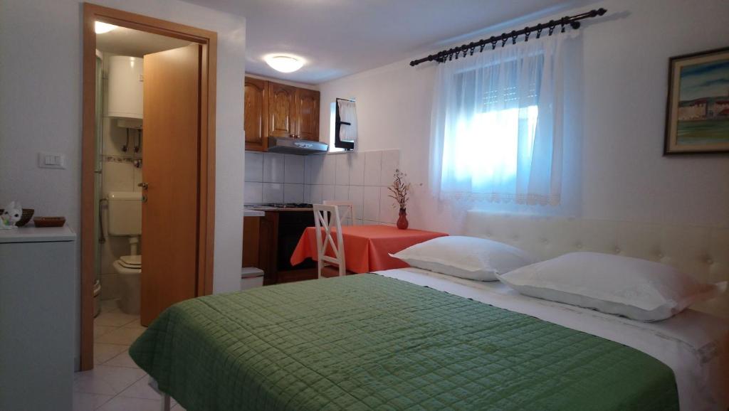 1 dormitorio con 1 cama verde y cocina en Apartment Marija, en Trogir