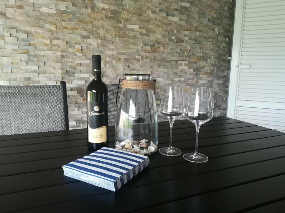 a bottle of wine and two wine glasses on a table at Apartment Sun & Sea in Krk