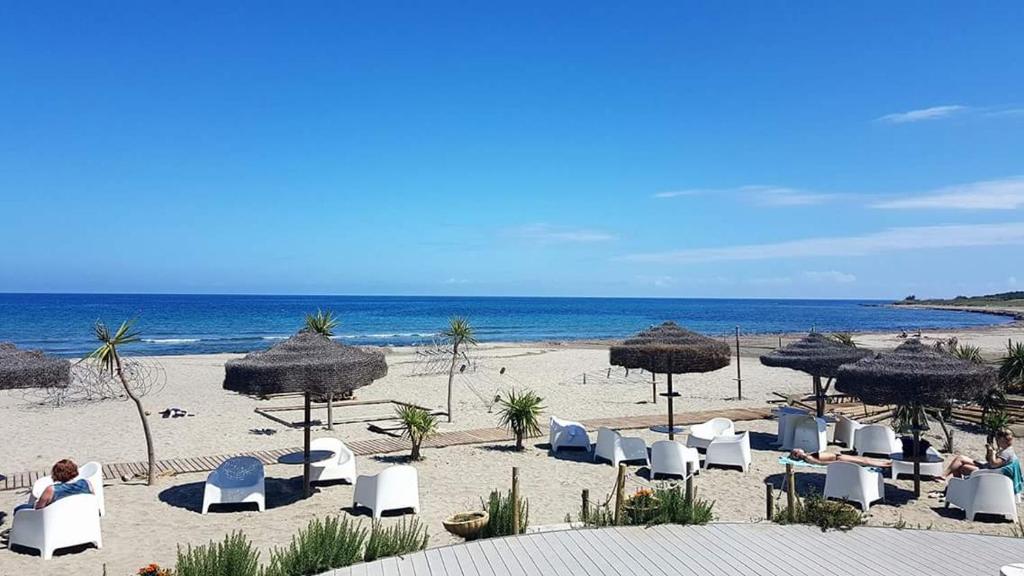 una spiaggia con sedie e ombrelloni e l'oceano di Corallo casa vacanza a Villaputzu