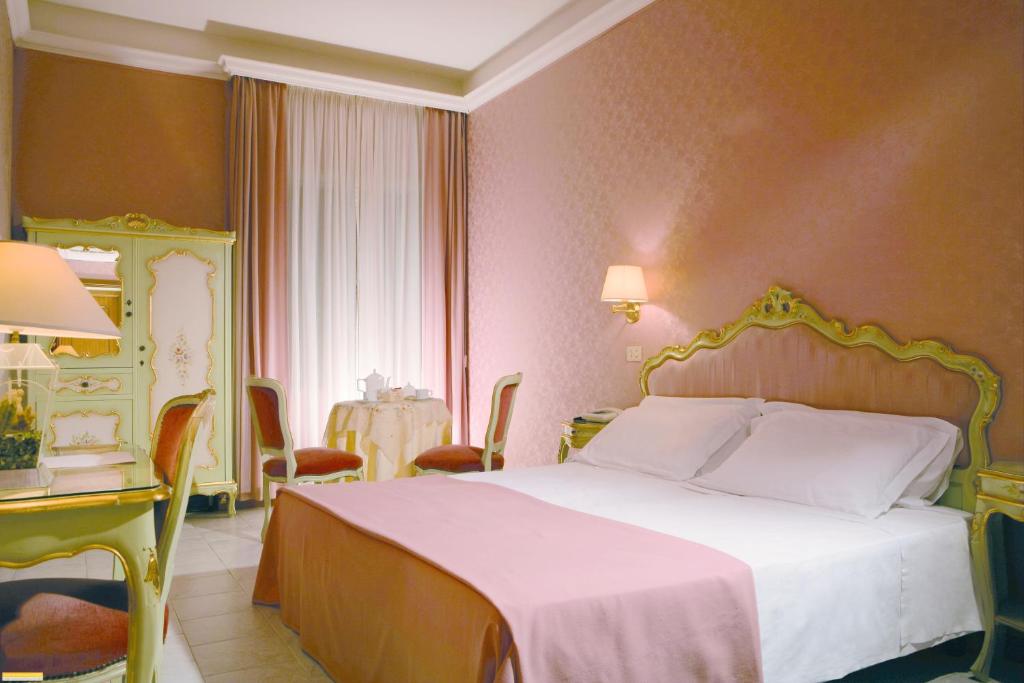 a bedroom with a white bed and a table and chairs at Hotel Romulus in Rome