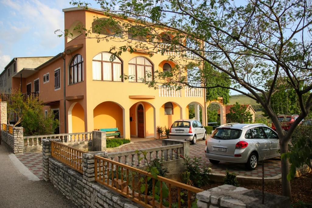 ein gelbes Haus mit davor geparkt in der Unterkunft Apartment Nakić in Vrpolje