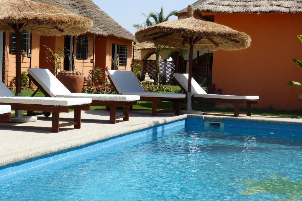 a resort with a swimming pool with chairs and umbrellas at Terra Lodge Sénégal in Mbour