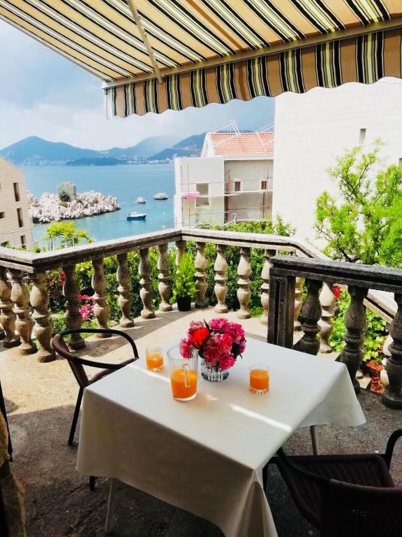 a table with orange juice and flowers on a balcony at Luxury Apartment Stefan in Sveti Stefan