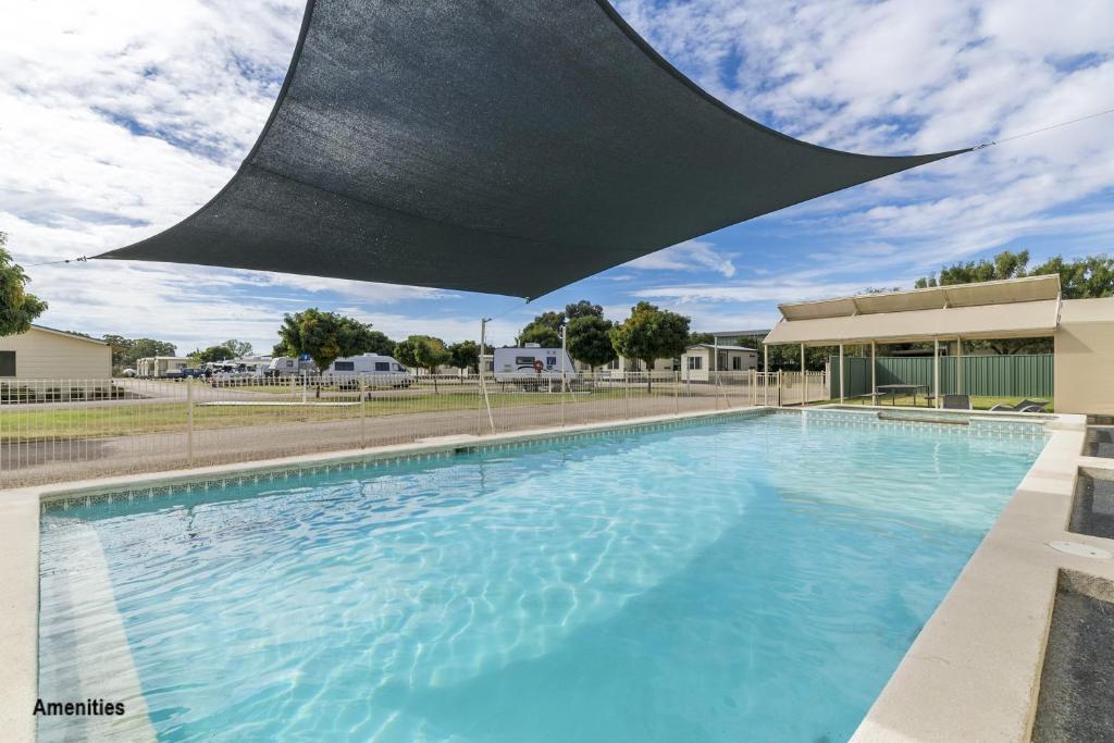 a swimming pool with a blue umbrella over it at Benalla Tourist Park in Benalla