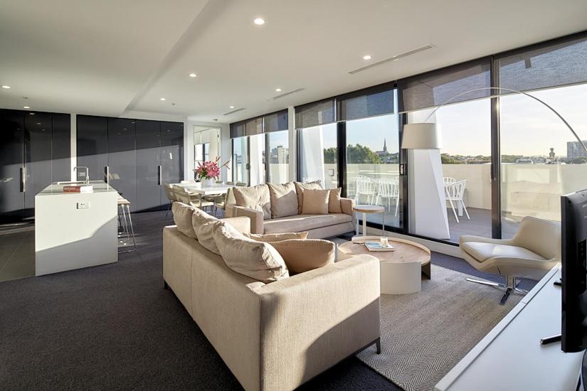 a living room with couches and a table and a kitchen at 381 Cremorne in Melbourne
