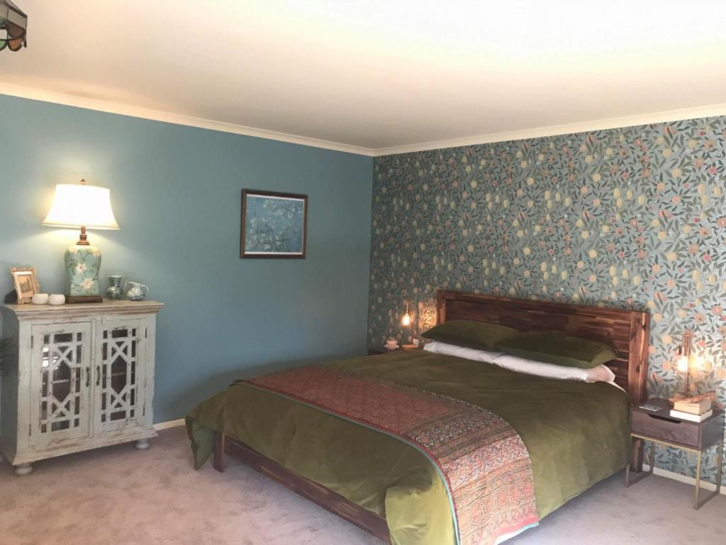 um quarto com uma cama e uma parede azul em Glascroft Gardens - Bed & Breakfast em Patea